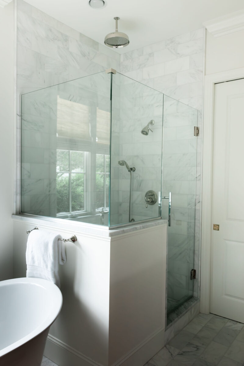 Honed marble shower with polished nickel rain shower head and glass enclosure | Twin Construction 
